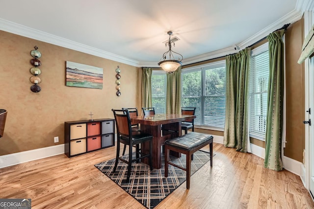 dining space with crown molding, baseboards, light wood finished floors, and visible vents