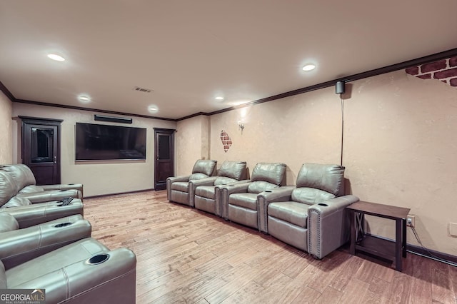 home theater room with baseboards, visible vents, ornamental molding, and wood finished floors