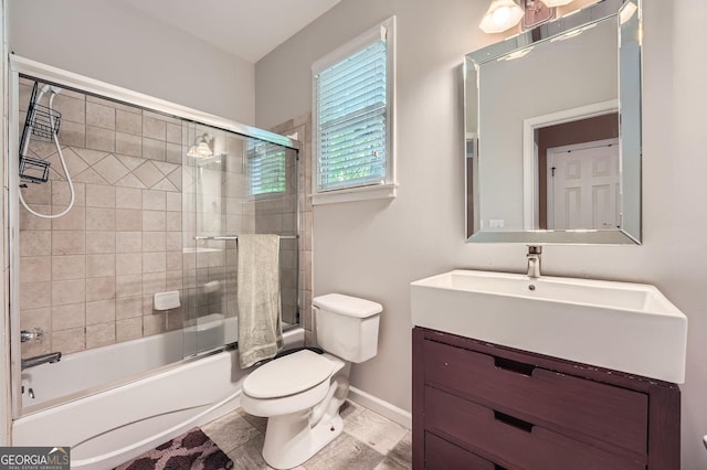 bathroom featuring toilet, baseboards, shower / bath combination with glass door, and vanity