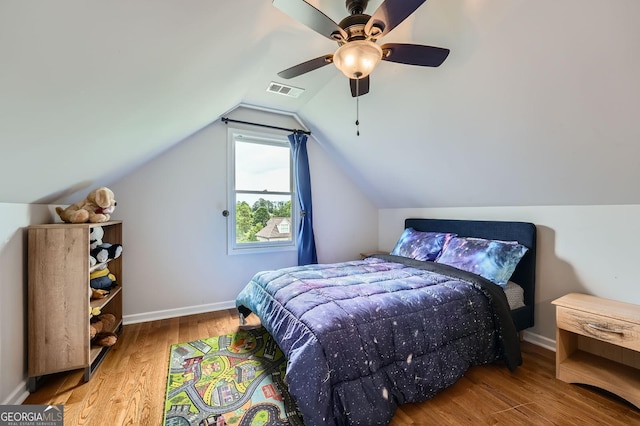 bedroom featuring lofted ceiling, baseboards, visible vents, ceiling fan, and wood finished floors