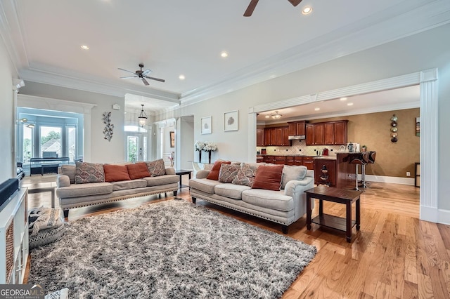 living room with a ceiling fan, baseboards, recessed lighting, light wood-type flooring, and ornamental molding