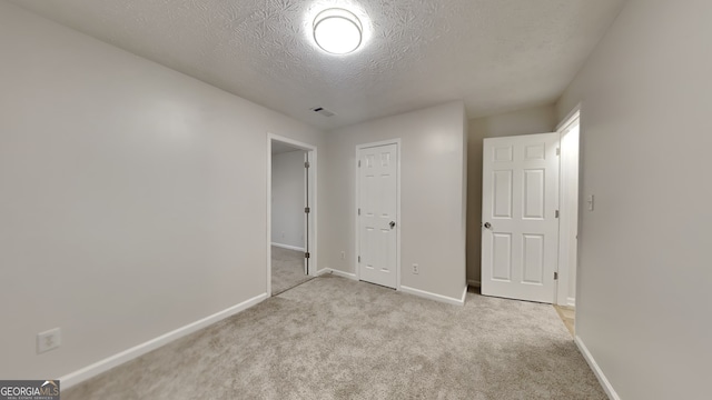 943 Colvin Dr, Locust Grove, GA 30248 - unfurnished bedroom with visible vents, a textured ceiling, baseboards, and light carpet