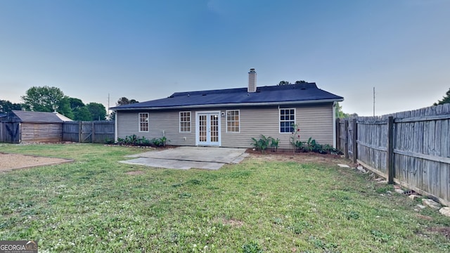 943 Colvin Dr, Locust Grove, GA 30248 - back of property with a fenced backyard, french doors, a chimney, a patio area, and a yard