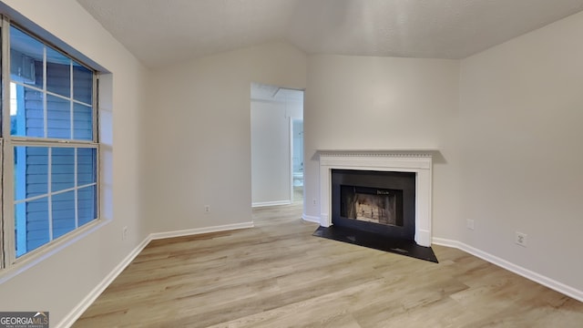943 Colvin Dr, Locust Grove, GA 30248 - unfurnished living room featuring a fireplace with flush hearth, baseboards, wood finished floors, and lofted ceiling