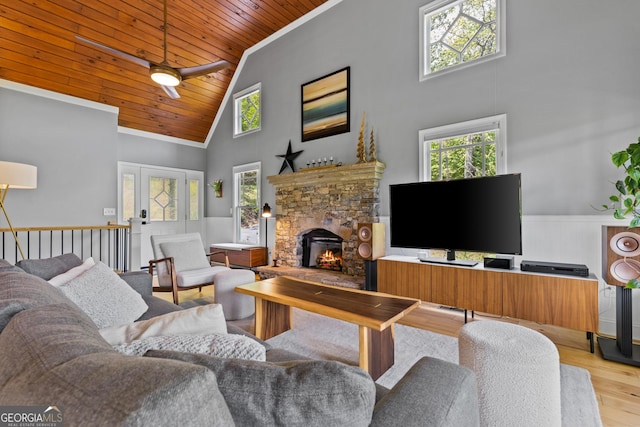 living area with wood finished floors, a stone fireplace, high vaulted ceiling, wooden ceiling, and a ceiling fan