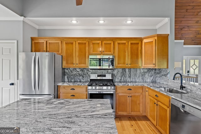 kitchen with crown molding, stainless steel appliances, a sink, and light wood-style flooring