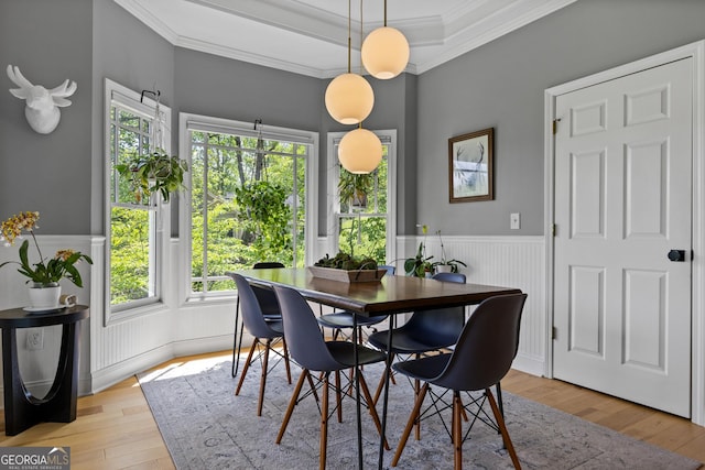 dining room with light wood-style floors, ornamental molding, and a wainscoted wall