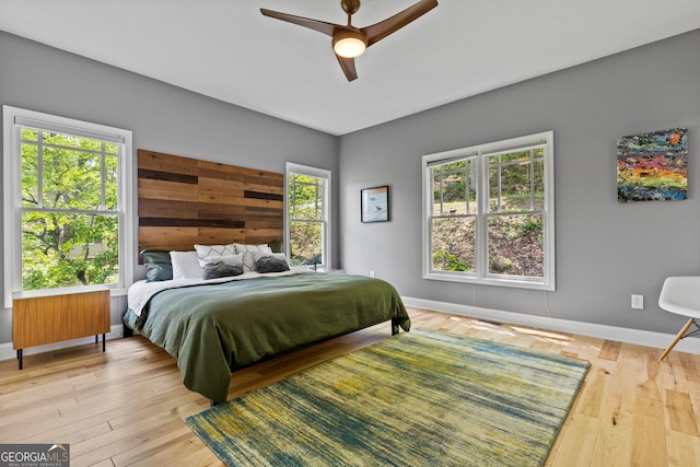 bedroom with baseboards, a ceiling fan, wood finished floors, and multiple windows