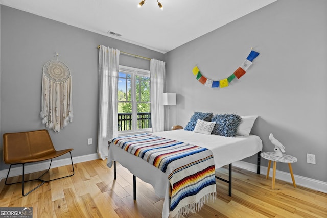 bedroom featuring baseboards, access to exterior, wood finished floors, and visible vents