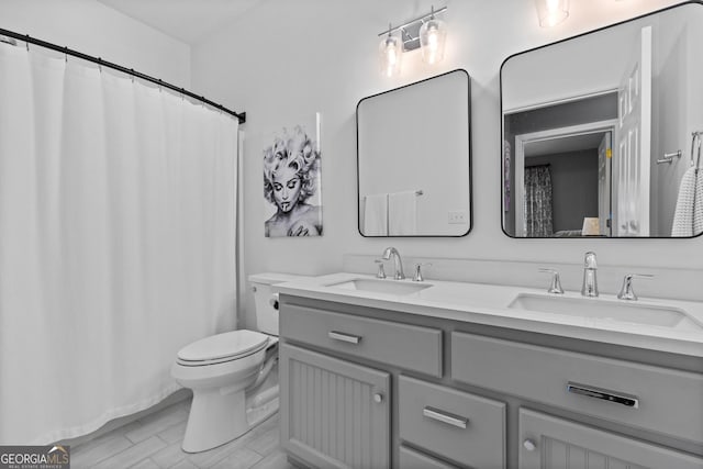 bathroom with double vanity, a sink, and toilet
