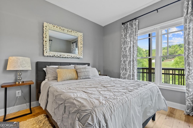 bedroom with baseboards, multiple windows, and wood finished floors