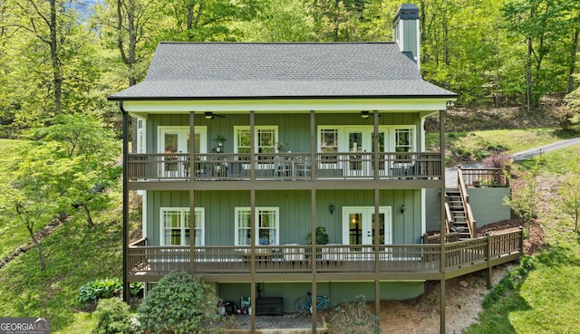 back of house with roof with shingles, stairs, a wooden deck, a chimney, and french doors