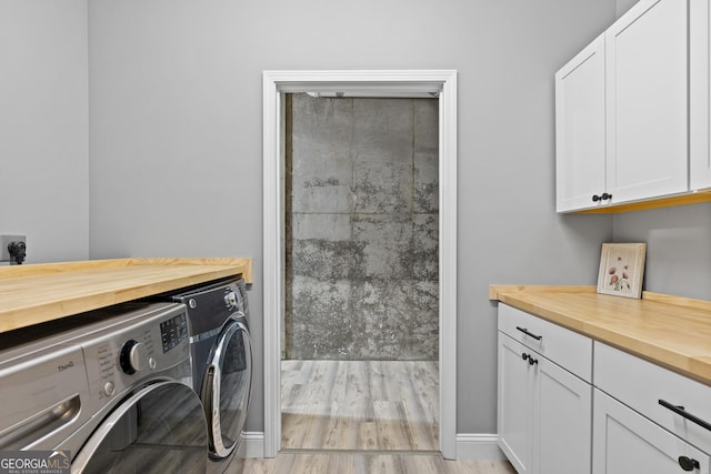 laundry room featuring baseboards, cabinet space, light wood-type flooring, and independent washer and dryer