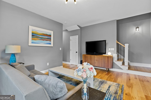 living area featuring stairs, baseboards, and light wood-type flooring