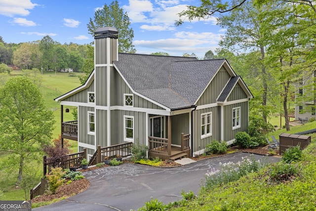 view of front of property with a porch, board and batten siding, a chimney, and roof with shingles