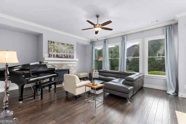 sitting room featuring ceiling fan, a stone fireplace, a wealth of natural light, and wood finished floors