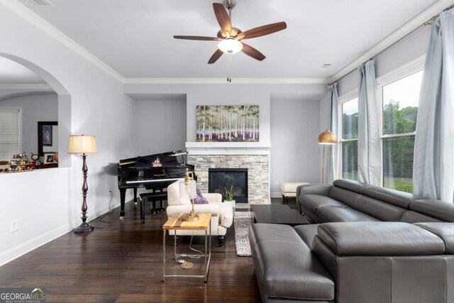 living room with arched walkways, a ceiling fan, a stone fireplace, and wood finished floors