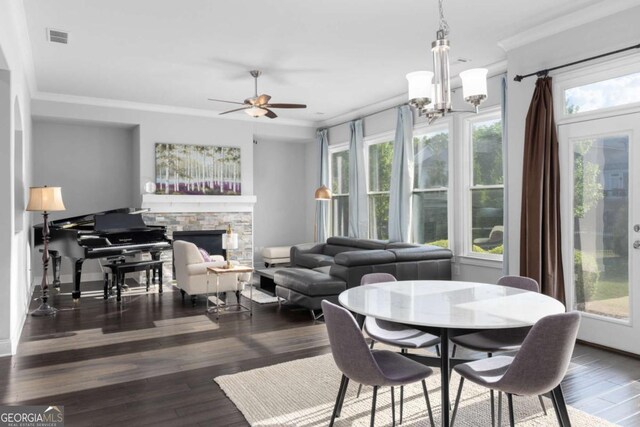 dining space with visible vents, ornamental molding, wood finished floors, and a stone fireplace