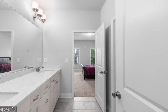 bathroom featuring ensuite bathroom, a sink, baseboards, and double vanity