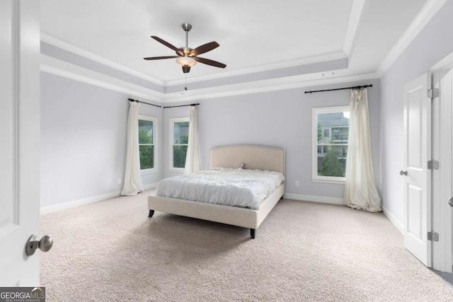 carpeted bedroom featuring baseboards, ornamental molding, and a tray ceiling