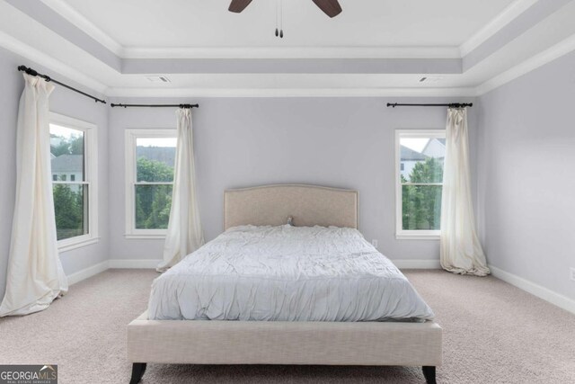carpeted bedroom with crown molding, a tray ceiling, ceiling fan, and baseboards