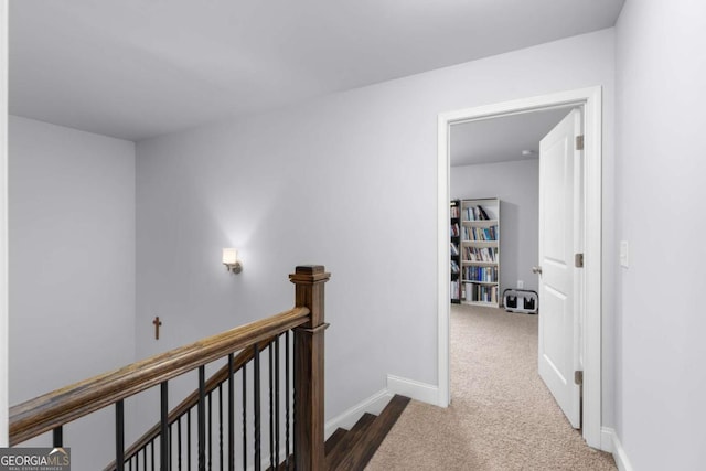 hall with baseboards, carpet, and an upstairs landing