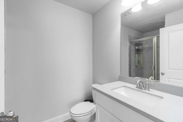 full bathroom featuring visible vents, vanity, toilet, baseboards, and a stall shower