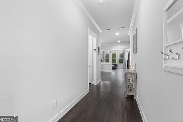 hallway featuring baseboards, ornamental molding, dark wood finished floors, and visible vents