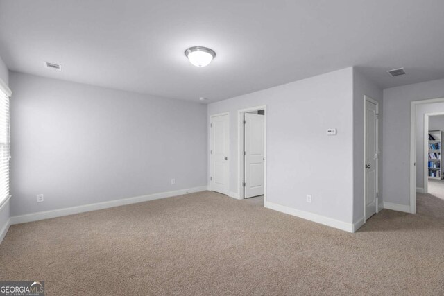 unfurnished bedroom with carpet flooring, baseboards, visible vents, and multiple windows