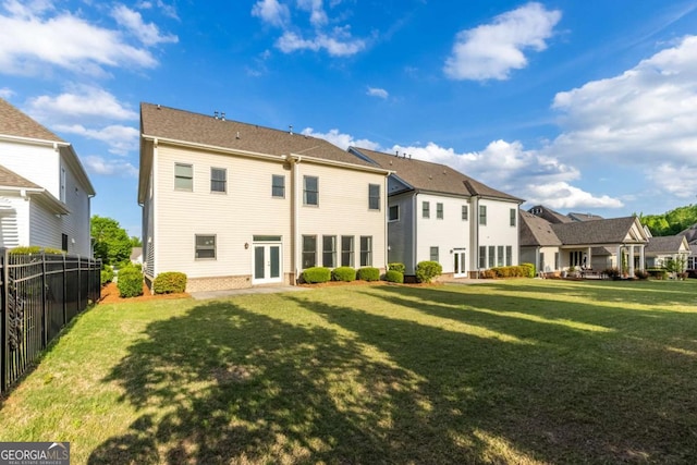 rear view of property featuring a lawn, fence, french doors, and a residential view