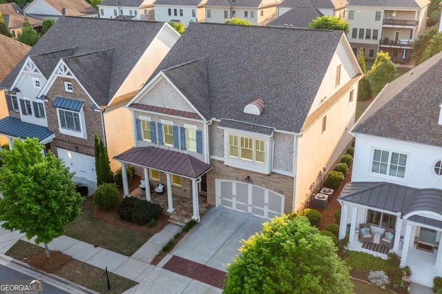 view of front facade with a porch, a residential view, a garage, central AC, and concrete driveway