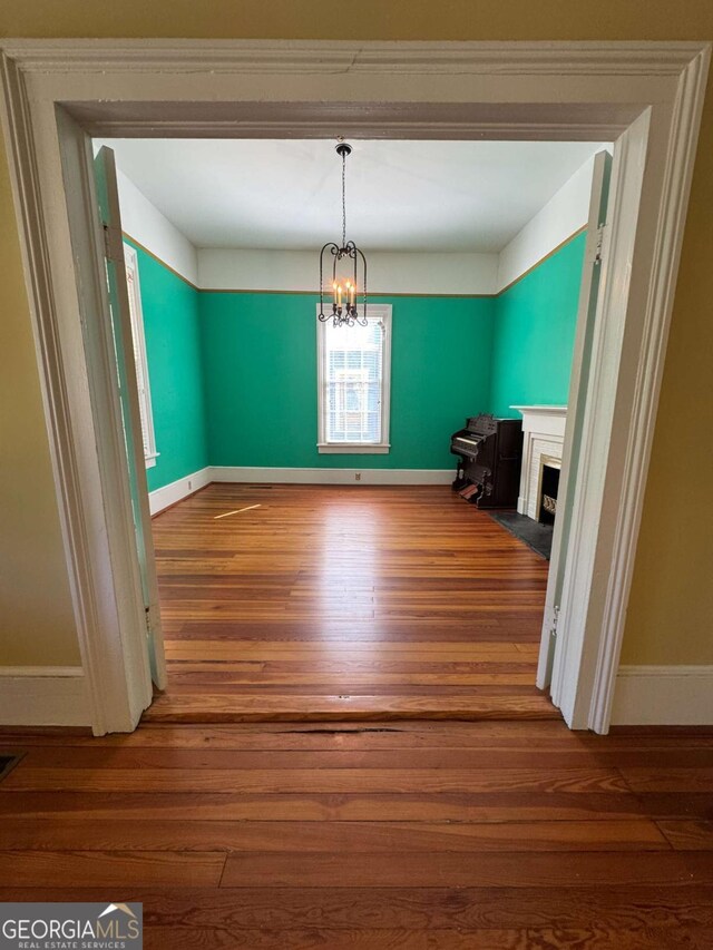 589 Meigs St, Athens, GA 30601 - unfurnished dining area featuring visible vents, a fireplace with flush hearth, wood finished floors, baseboards, and an inviting chandelier