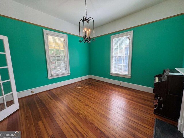589 Meigs St, Athens, GA 30601 - empty room with baseboards, hardwood / wood-style flooring, and an inviting chandelier