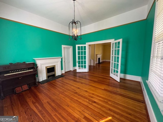 589 Meigs St, Athens, GA 30601 - unfurnished living room with a brick fireplace, wood finished floors, baseboards, a chandelier, and french doors