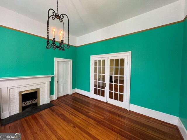 589 Meigs St, Athens, GA 30601 - unfurnished living room with french doors, a brick fireplace, wood finished floors, baseboards, and a chandelier