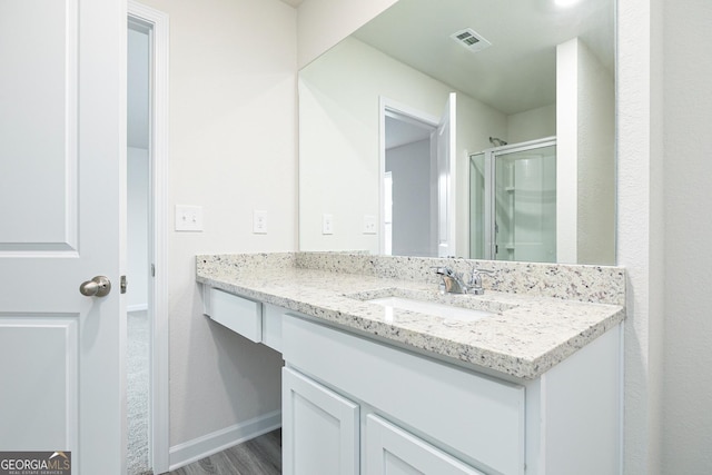 full bath featuring vanity, baseboards, a shower stall, wood finished floors, and visible vents