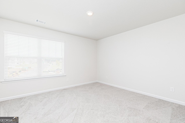 carpeted empty room featuring baseboards and visible vents