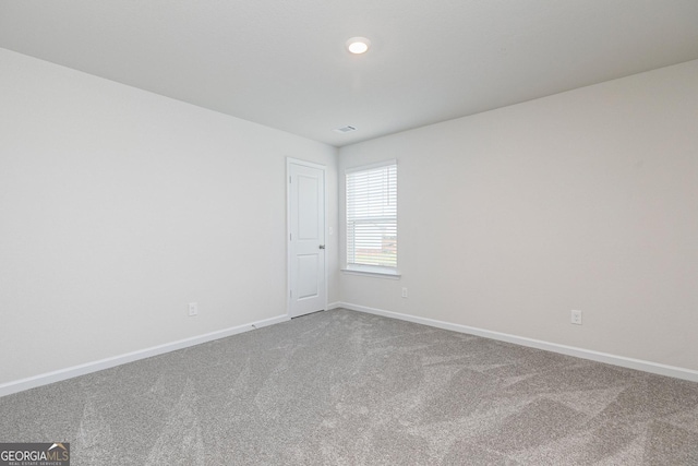 spare room with carpet flooring, baseboards, and visible vents