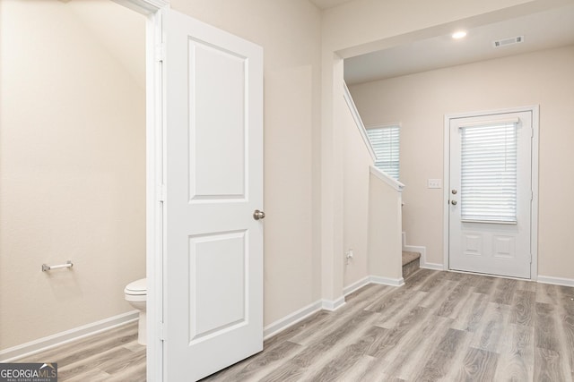 entryway with light wood-style floors, baseboards, stairs, and visible vents