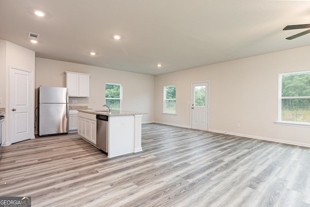 kitchen with a sink, appliances with stainless steel finishes, light wood finished floors, and open floor plan