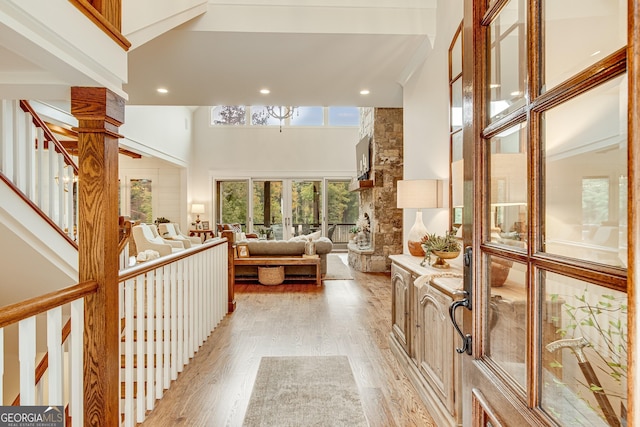 hallway with recessed lighting, a high ceiling, and light wood finished floors