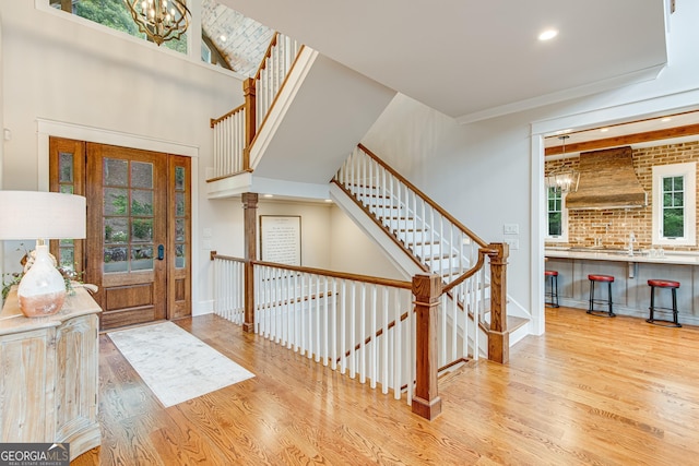 foyer entrance with stairs, recessed lighting, a notable chandelier, and wood finished floors