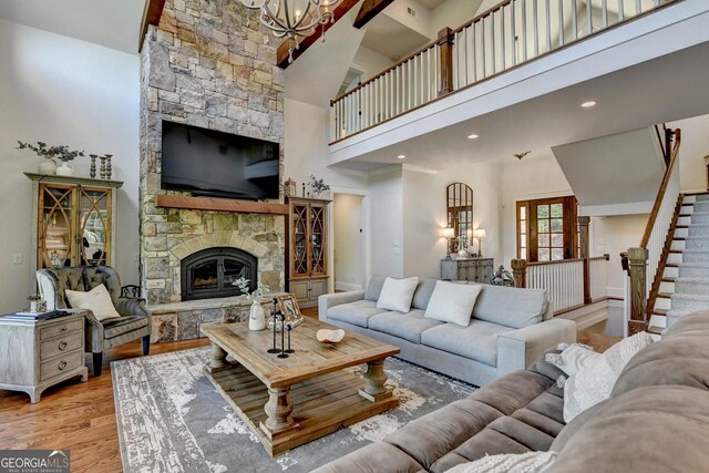 676 N Shore Dr, Cleveland, GA 30528 - living room featuring a towering ceiling, a chandelier, wood finished floors, a stone fireplace, and stairs