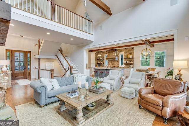 living area with high vaulted ceiling, beam ceiling, stairs, and wood finished floors