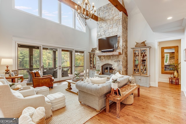 living room featuring light wood finished floors, a fireplace, high vaulted ceiling, a chandelier, and french doors