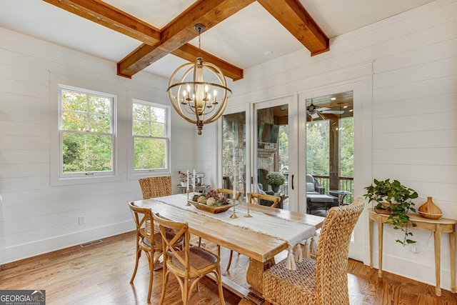 dining space with wooden walls, light wood-style floors, and visible vents