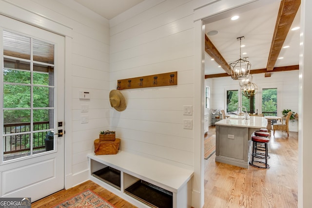 mudroom with wooden walls, an inviting chandelier, plenty of natural light, and light wood finished floors