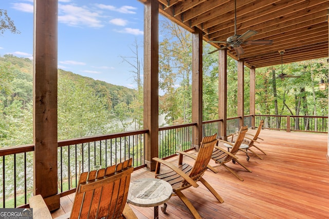 wooden deck with a ceiling fan and a forest view
