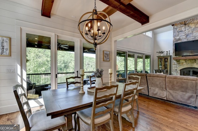676 N Shore Dr, Cleveland, GA 30528 - dining space featuring beamed ceiling, wood finished floors, a chandelier, a fireplace, and wood walls