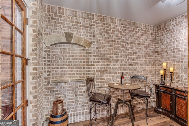 dining area with wood finished floors and brick wall